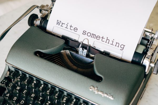 Machine à écrire avec un papier où il est écrit "Write something"