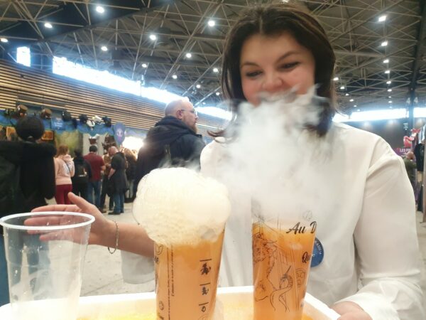 Émilie en train d'apporter des boissons du dragon qui fume : plateau avec deux verres fumants.