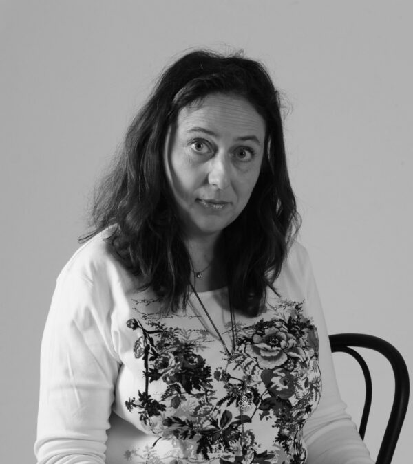 Nathalie Bagadey assise sur une chaise, en train de regarder en face d'un air perplexe. Photo Noir et Blanc.