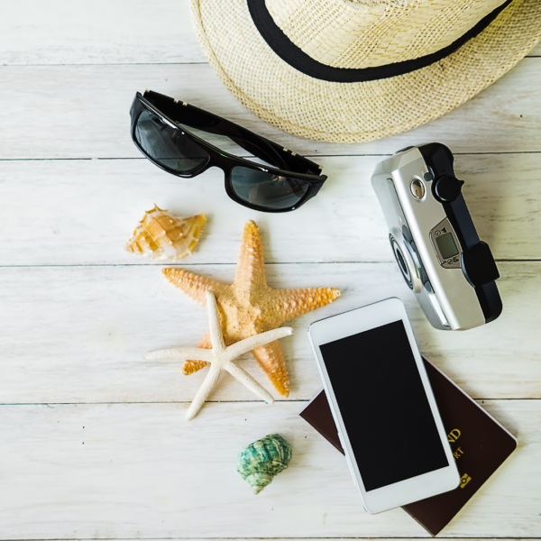 Image Canva Pro représentant des coquillages, des lunettes de soleil, un chapeau de paille, un appareil photo et un téléphone portable sur un sol en caillebotis blanc